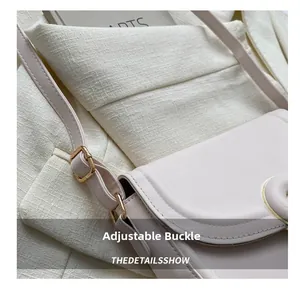 Detail shot of the adjustable gold-tone buckle on the beige minimalist saddle bag strap