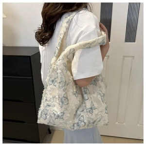 Detail of cream plush tote bag with light blue butterfly jacquard and raw edges