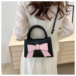 Detail of crossbody mini bag with large pink bow and slim strap shown on model back