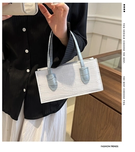 Detail of white crocodile embossed leather handbag with light blue handles and zip closure