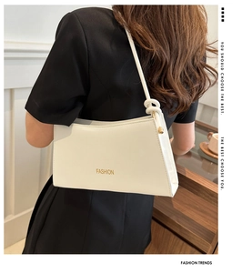 Détail du sac sous l'aisselle blanc avec sangle nouée et accents métalliques dorés