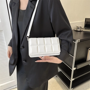 White minimalist quilted rectangular crossbody bag with shoulder strap worn by a model