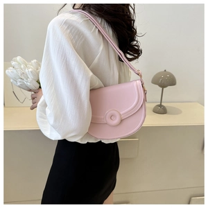 Side view of pink PU leather saddle bag with round buckle and adjustable strap