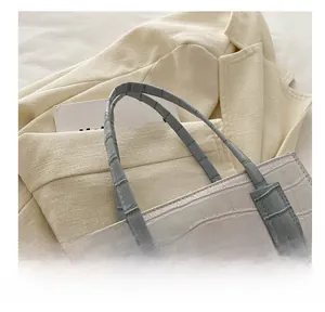 Detailed close-up of a light beige crocodile-patterned handbag with comfortable handles