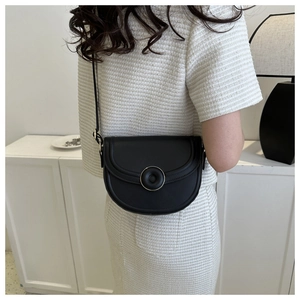 Detailed macro view of black matte saddle bag featuring a gold round metal buckle