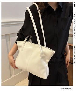 Close-up of a white glossy leather tote bag with elegant vertical stitching details