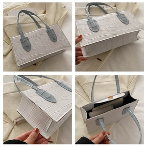 Detail view of crocodile textured handbag showing interior capacity and multi-angle design