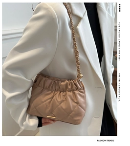 Close-up of beige quilted cloud bag with gold chain strap and elegant pleated texture
