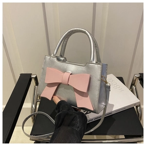 Detail of silver handbag featuring a large pink bow and sleek metallic finish