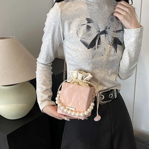 Pink pleated crossbody bag with pearl handle and gold chain strap shown on model