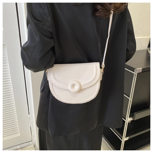Detailed view of white minimalist saddle bag with large decorative buckle on black suit
