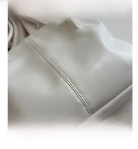 Detailed view of the textured off-white faux leather and precise vertical stitching of tote bag