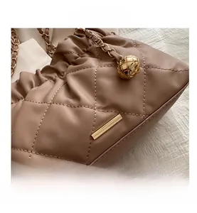 Close-up of brown quilted leather bag featuring gold chain strap and metal ball detail