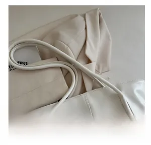 Detail of soft padded handles and litchi texture on a cream white tote bag