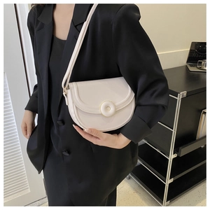 Macro detail of off-white faux leather saddle bag with matte finish and flap closure