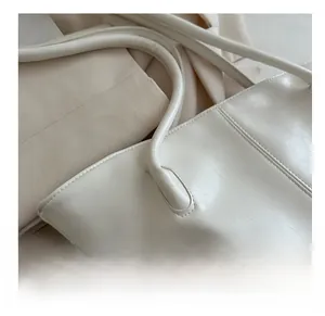 Close-up of off-white tote bag showing vintage leather texture and reinforced stitching