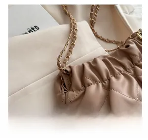 Detail of coffee brown quilted leather bag with elegant pleated design and gold chain strap