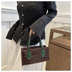 Detail of a retro faux crocodile leather handbag with contrasting dark red and green textures
