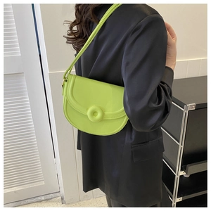 Detail of a bright green saddle bag on a black satin blazer showcasing vibrant color contrast
