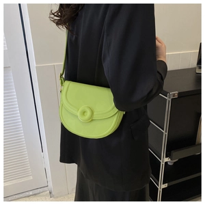 Neon green saddle bag styled on a black blazer for a high-contrast fashion look