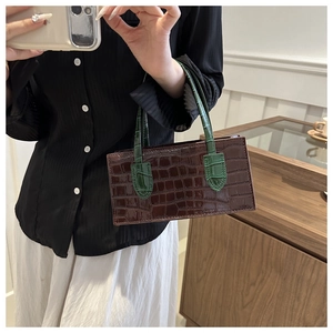 Detail of vintage rectangular handbag with brown crocodile texture and green handles