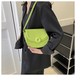 Detail of lime green saddle bag flap with matching round button and matte leather texture
