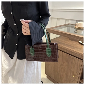 Close-up of rectangular retro handbag featuring brown crocodile texture and green handle