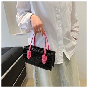 Close-up of black crocodile pattern handbag featuring a contrast pink handle design