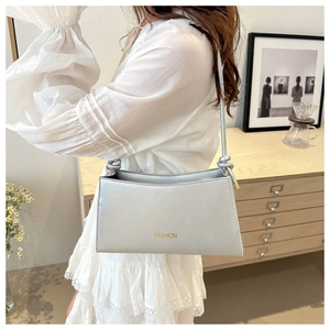 Détail du sac argenté en similicuir avec logo FASHION et bandoulière à nœuds élégante