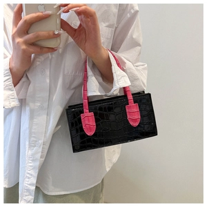 Detailed macro view of black crocodile pattern leather and neon pink handles on the handbag