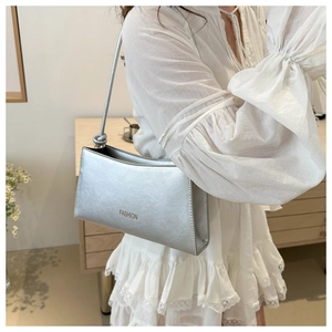 Détail du sac à bandoulière argenté métallisé avec texte FASHION et nœud décoratif sur l'anse