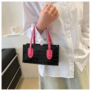 Detail of crocodile pattern handbag with contrast pink handle on a fashion model
