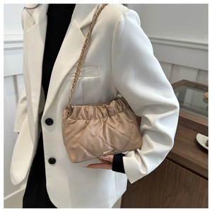 Detailed view of beige quilted bag with gold chain strap and elegant pleated top design