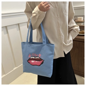 Dettaglio della borsa tote in tela azzurra con stampa labbra love e tracolla robusta