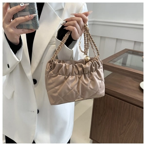Close-up of khaki quilted faux leather handbag with gold chain straps and pleated texture