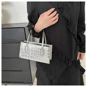 Silver crocodile texture mini square handbag shown on shoulder with black dress