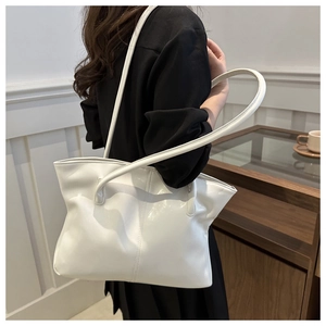 Detail of white glossy PU leather tote bag showing reflective texture and elegant strap