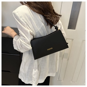 Détail du sac sous l'aisselle en cuir noir avec bandoulière à nœud sur un blazer blanc