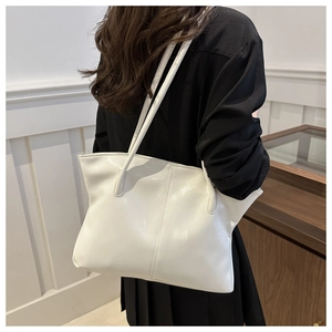 Detail of white glossy tote bag showing the shiny patent leather texture and stitching