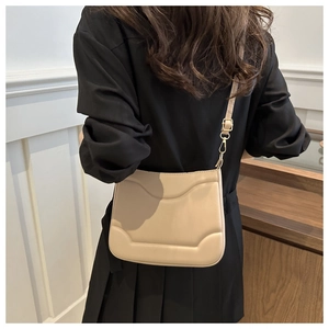 Dettaglio di borsa minimalista in pelle albicocca con goffratura e finiture in metallo oro