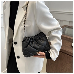 Detail of black quilted shoulder bag featuring gold-tone chain strap and premium texture