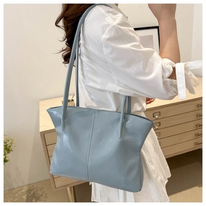 Detail of light blue tote bag showing glossy texture and vertical stitching on shoulder bag