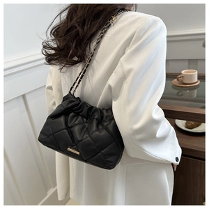 Detailed close-up of a quilted black leather shoulder bag with a gold metal chain strap