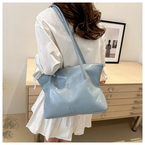Detail of light blue patent leather tote bag showing glossy texture and slim shoulder straps