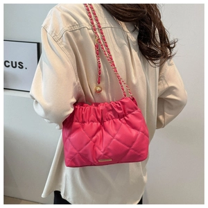 Detail of fuchsia quilted shoulder bag featuring gold chain and decorative metal ball