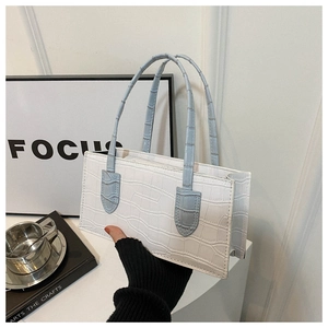 Detail view of white crocodile pattern shoulder bag with light blue top handles