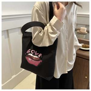 Borsa tote in tela nera con labbra rosa e scritta LOVE indossata da una donna