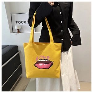 Dettaglio della borsa tote in tela gialla con motivo a labbra rosa e stampa LOVE artistica