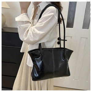 Close-up of black glossy patent leather tote bag with stylish white contrast stitching details