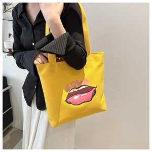 Dettaglio della borsa tote in tela gialla con stampa labbra rosse e grafica LOVE alla moda